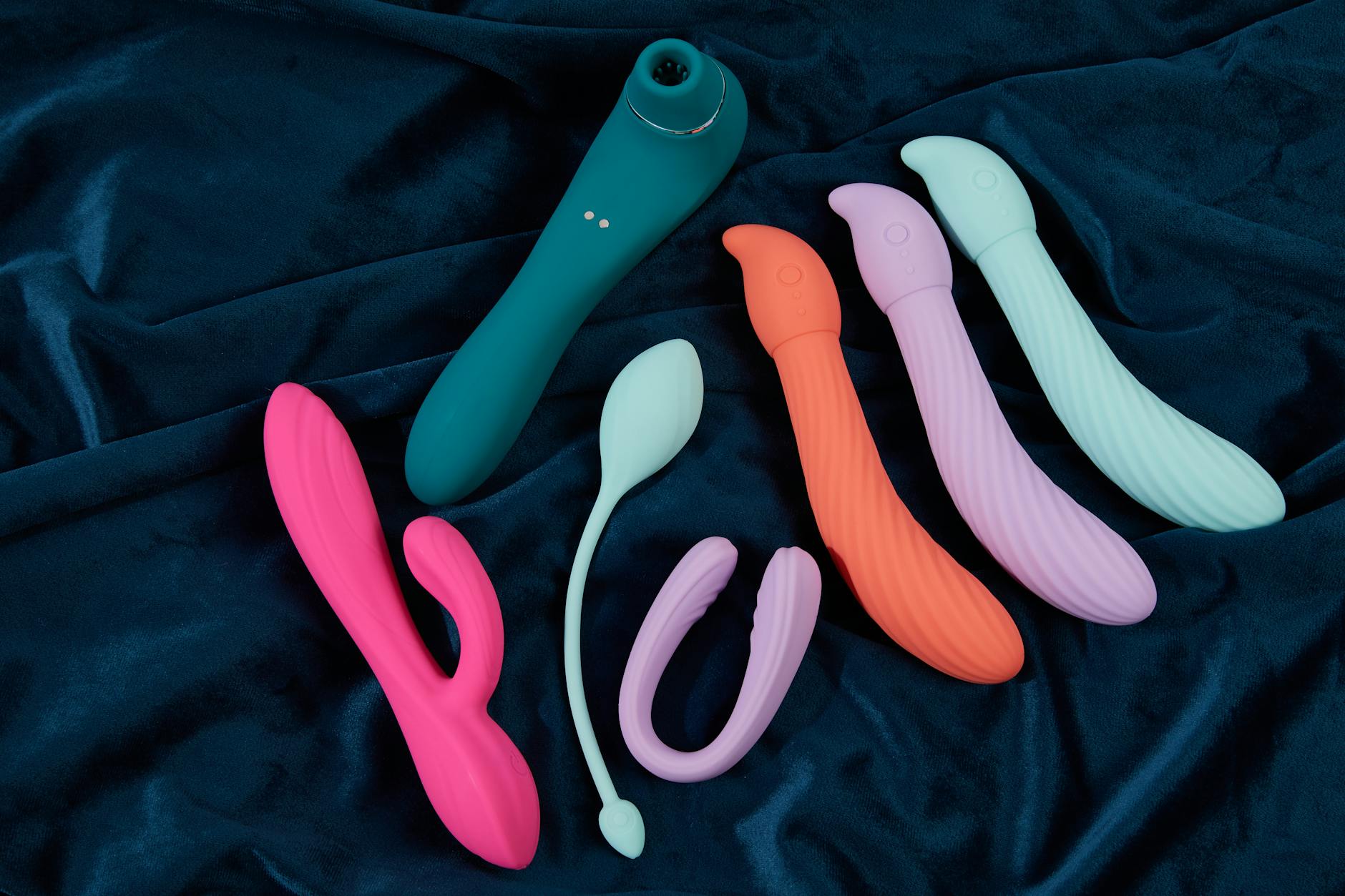 A young couple standing together indoors, holding a blue vibrator together, symbolizing modern intimacy and openness
