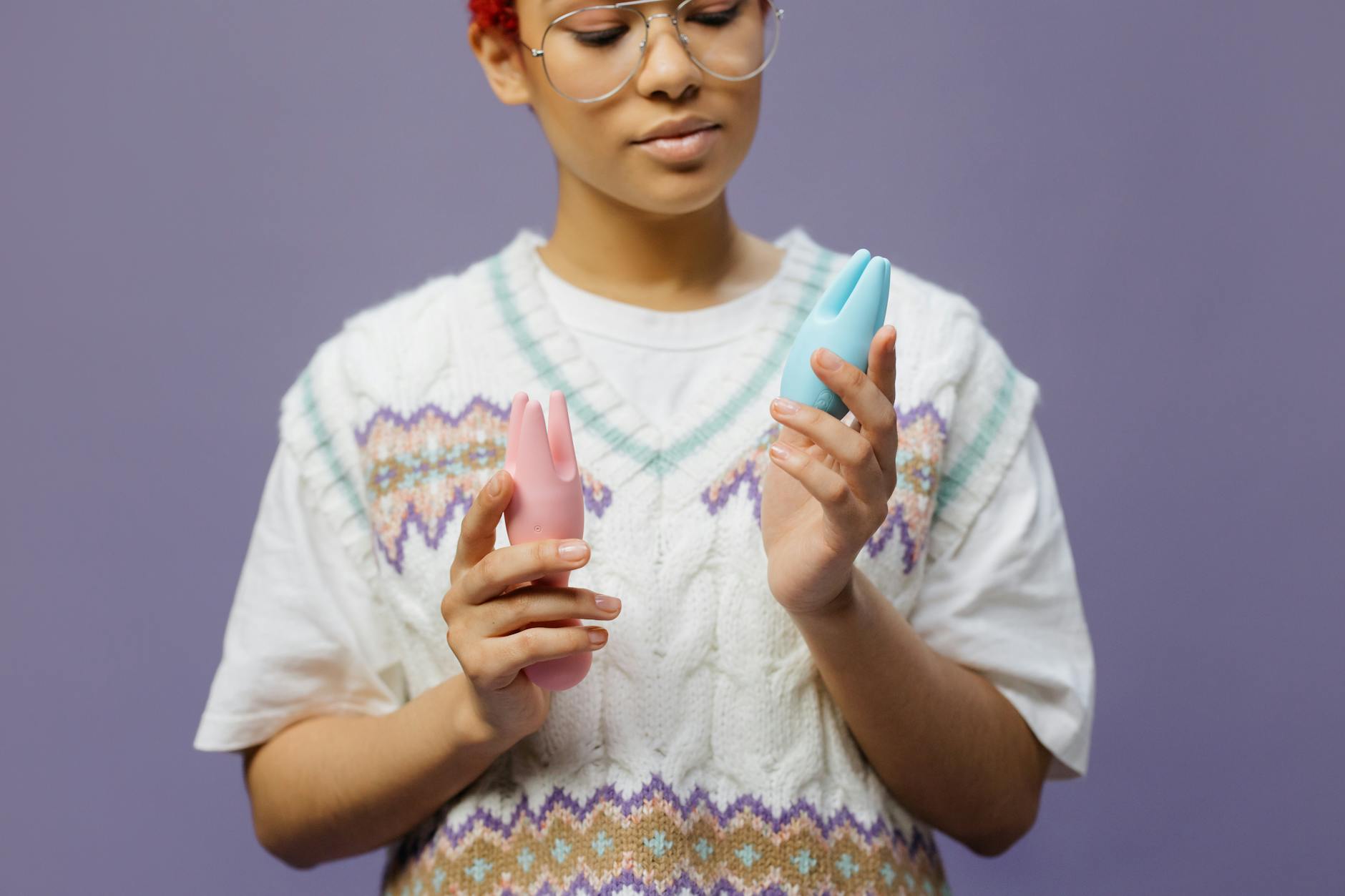 Woman holding blue and pink lemon vibrators in a contemplative moment.