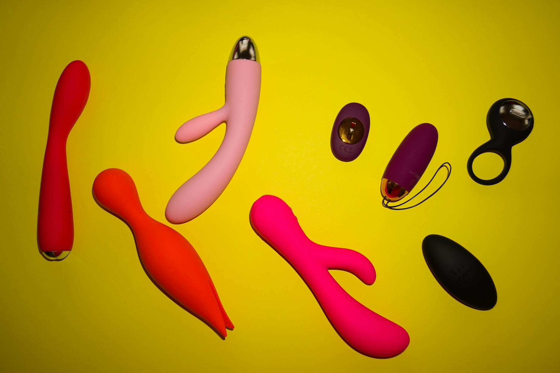 Vibrant collection of lemon and colorful clitoral vibrators arranged on bright yellow surface